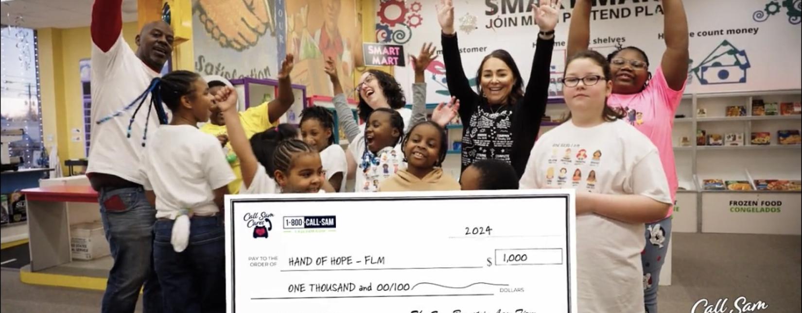 people and kids standing behind giant card board check