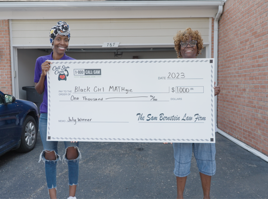 two women standing behind giant card board check
