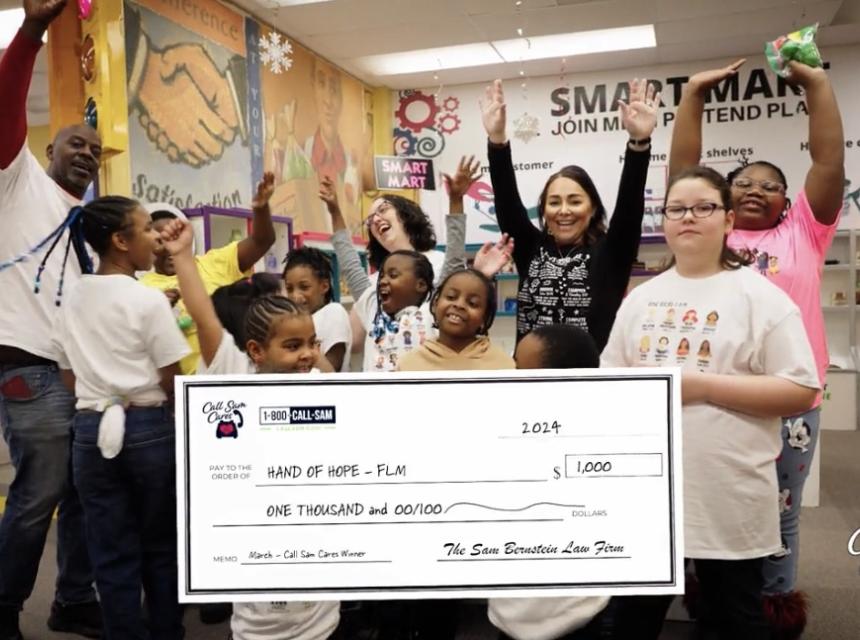 people and kids standing behind giant card board check