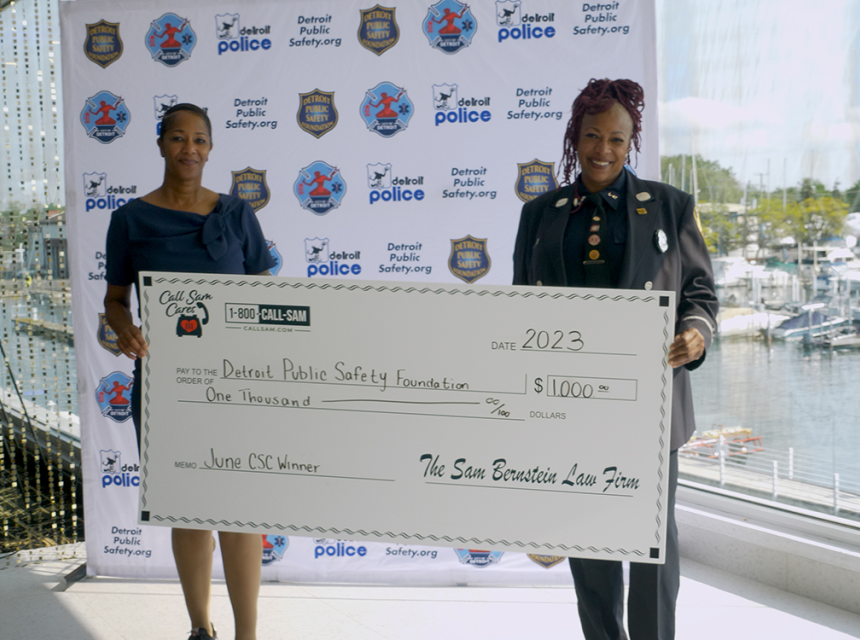 two women standing behind giant card board check